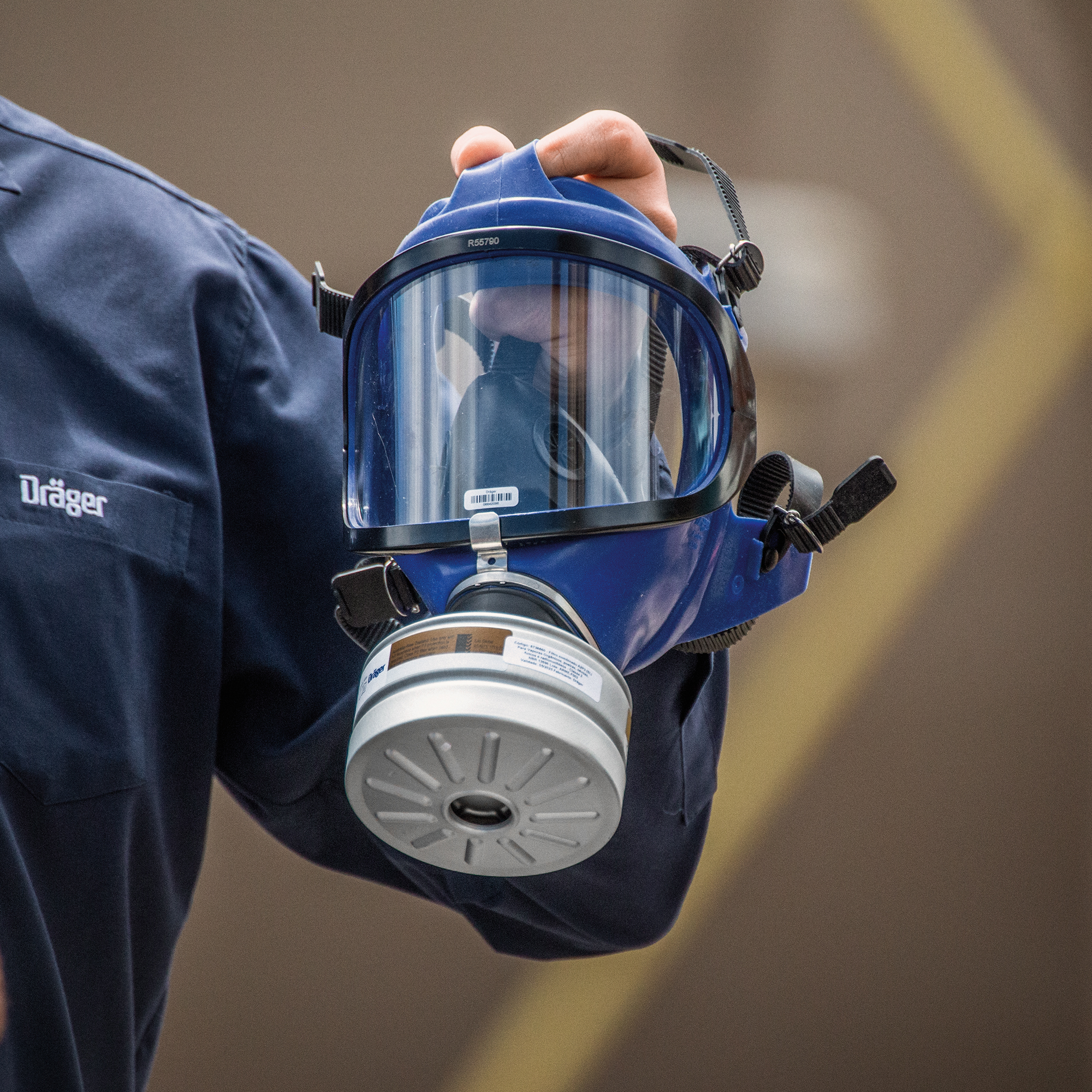 Person hält eine blaue Atemschutzmaske mit Filter von Dräger in der Hand.