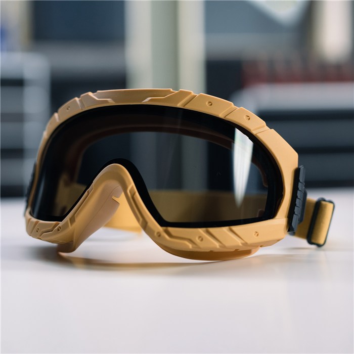 Schutzbrille Dräger X-pect 4900, sandfarben Sandfarbene Schutzbrille mit dunklem Glas auf hellem Tisch.