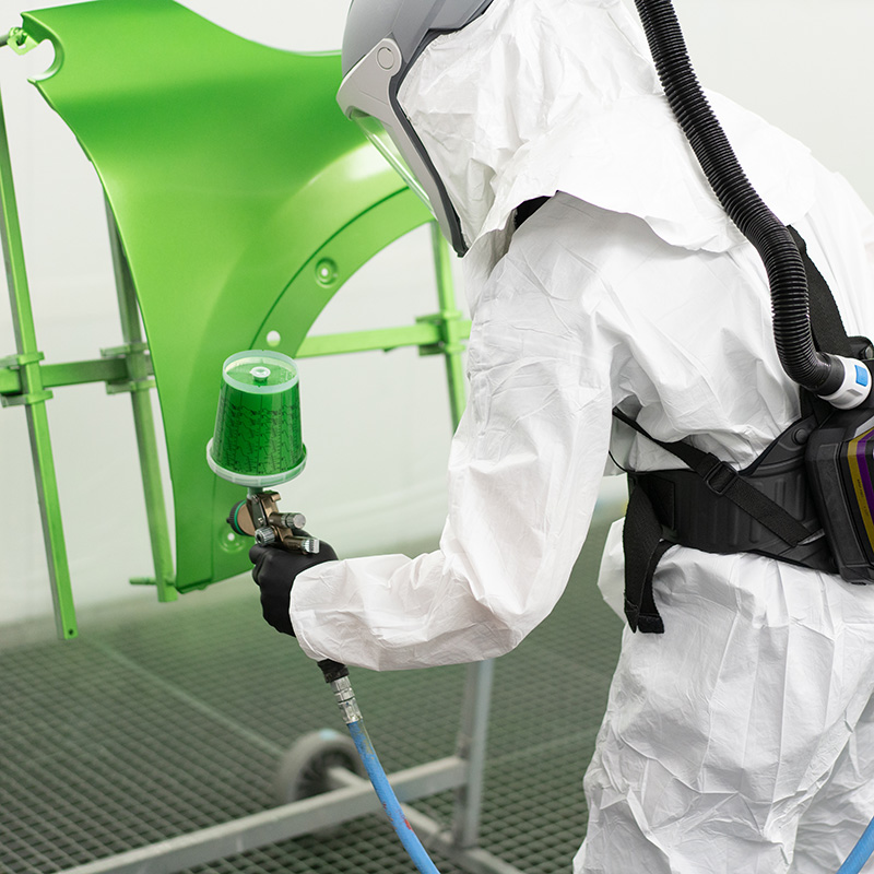X-plore 8000 Lackierschutzsystem Person mit Atemschutzgerät beim Lackieren eines Autoteils.