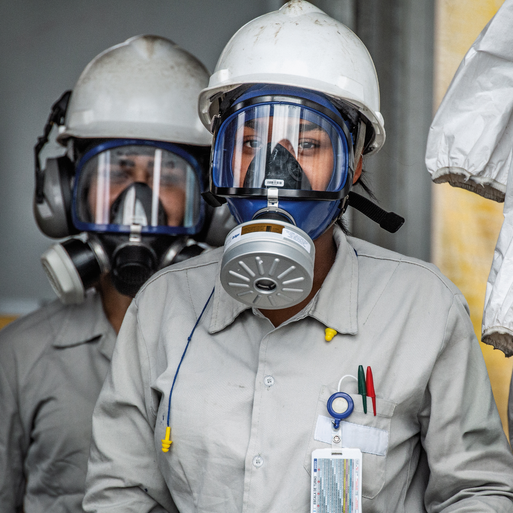 Personen tragen Helme und Atemschutzmasken mit Filter.