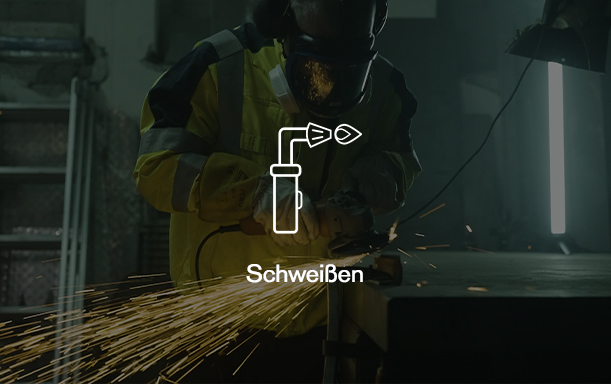 Sicherheit beim Schweißen Arbeiter mit Schutzkleidung beim Schweißen, Funkenflug sichtbar.