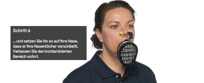 Person demonstriert Anlegen eines Fluchtgeräts auf der Nase.
