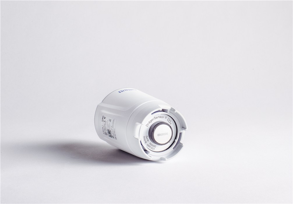 Weißer zylindrischer CO2-Sensor liegt auf weißer Fläche.