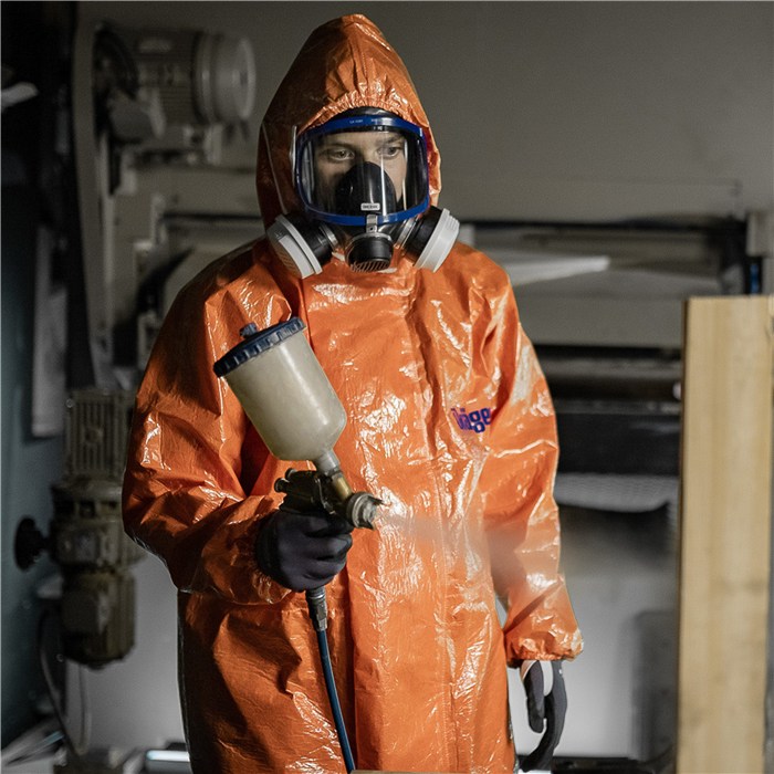 Sicherheitsanzug für Chemikalien Person im orangefarbenen Schutzanzug mit Atemschutz und Sprühgerät.