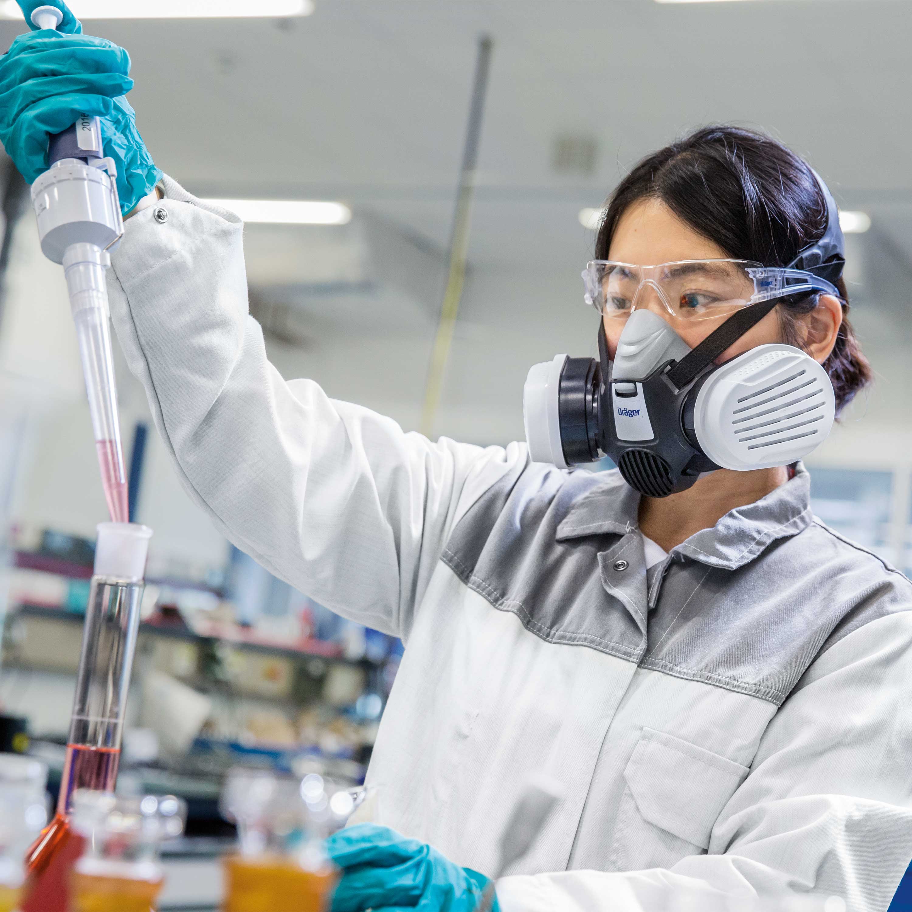 Person im Labor mit Dräger X-plore 3300 Halbmaske beim Pipettieren.