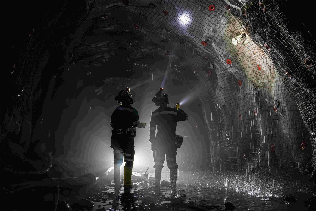 Sicherheitstechnik im Tunnelbau Zwei Personen in Schutzkleidung inspizieren beleuchteten Tunnel.