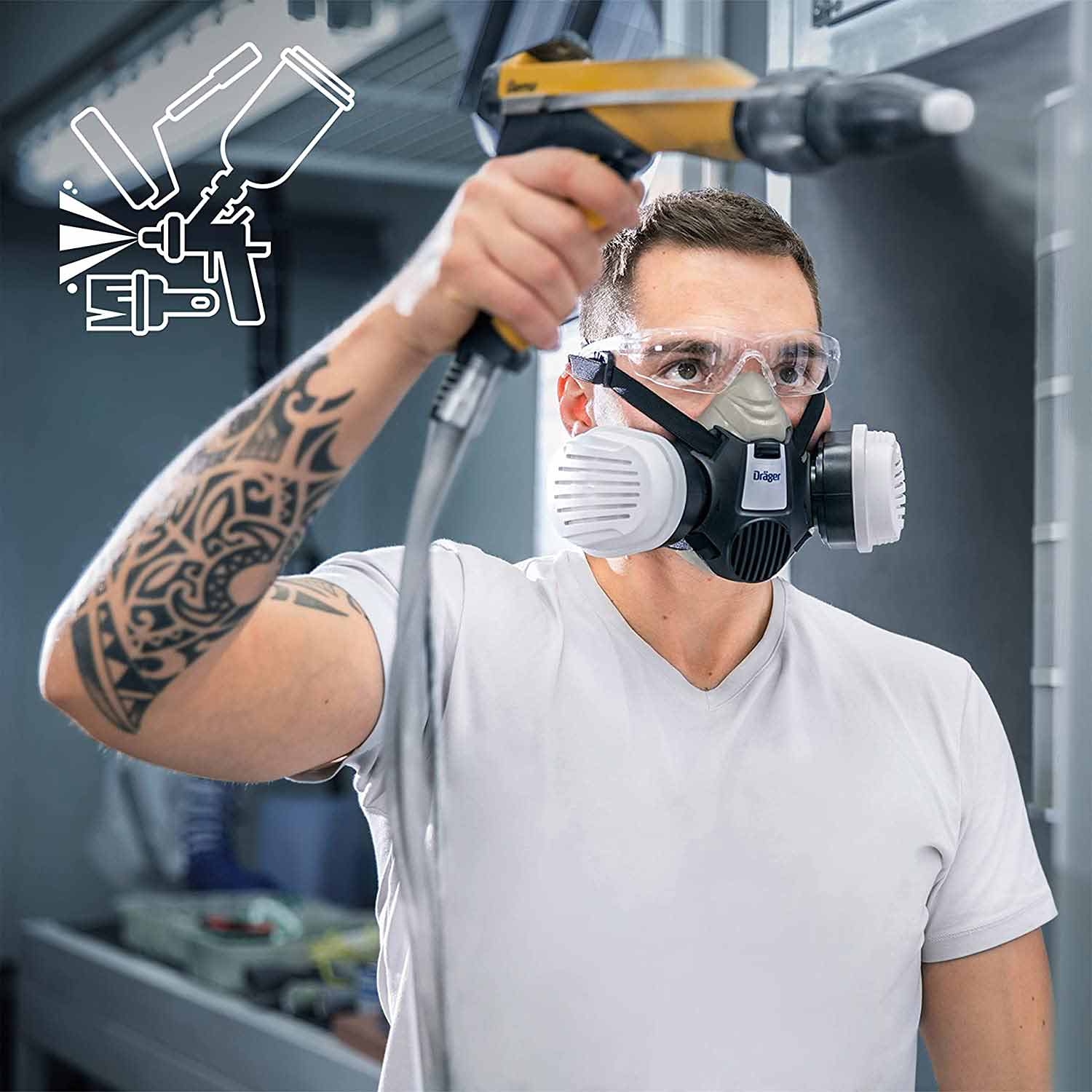 Person sprüht mit Schutzmaske und Filter in Werkstattumgebung.