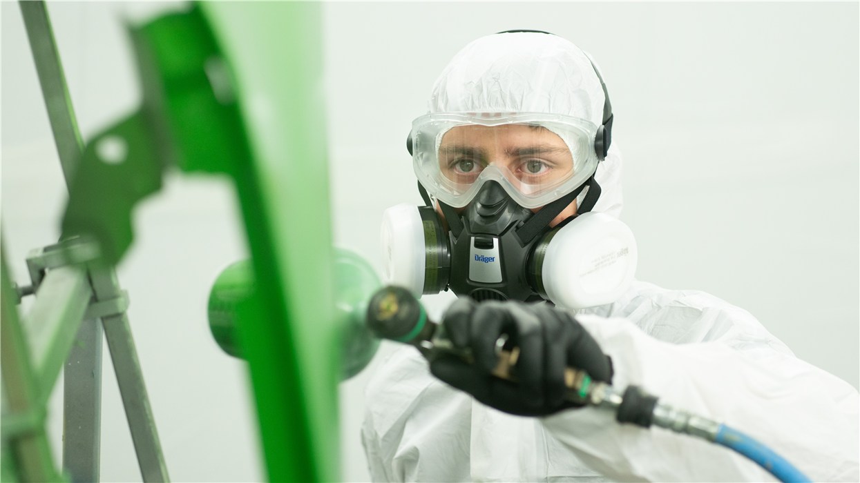 Schutzkleidung bei Sicherheitsanwendungen Person in Schutzausrüstung verwendet eine Sprühpistole.
