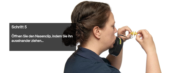 Anleitung: Fluchtgerät Nasenclip öffnen Person öffnet Nasenclip eines Fluchtgeräts durch Auseinanderziehen.