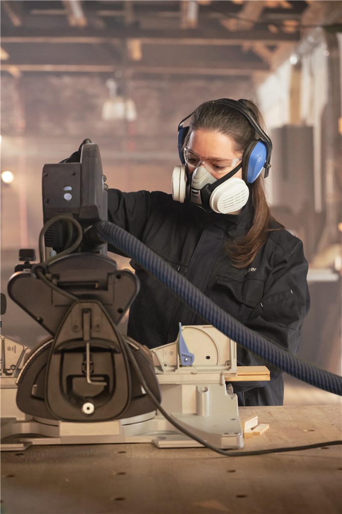 Arbeitssicherheit in der Holzverarbeitung Person in Schutzkleidung an Holzbearbeitungsmaschine.