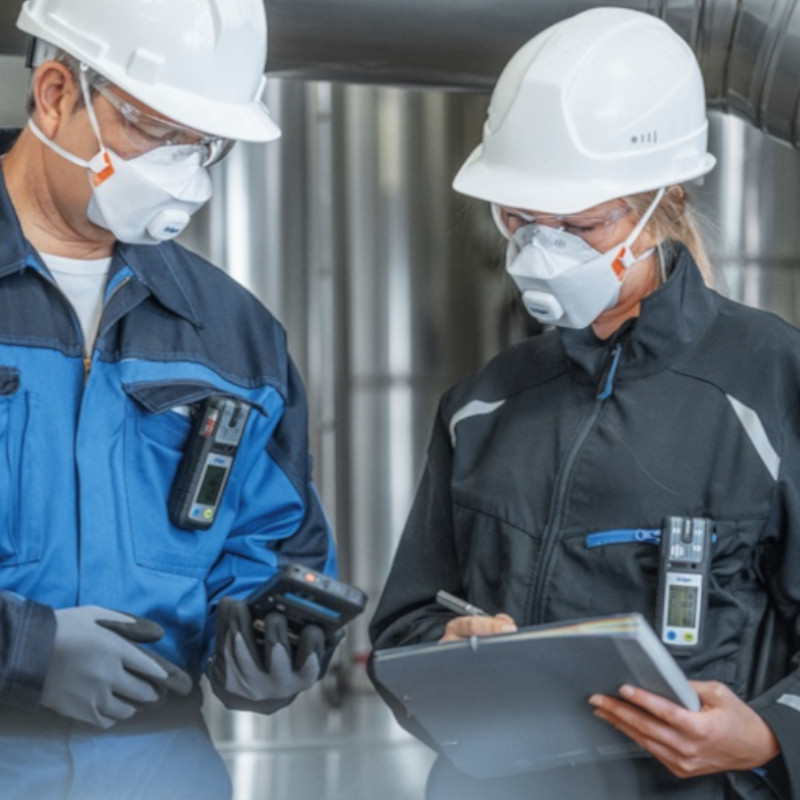 2 Personen im industriellen Umfeld mit dem X-am 2800 an der Kleidung befestigt