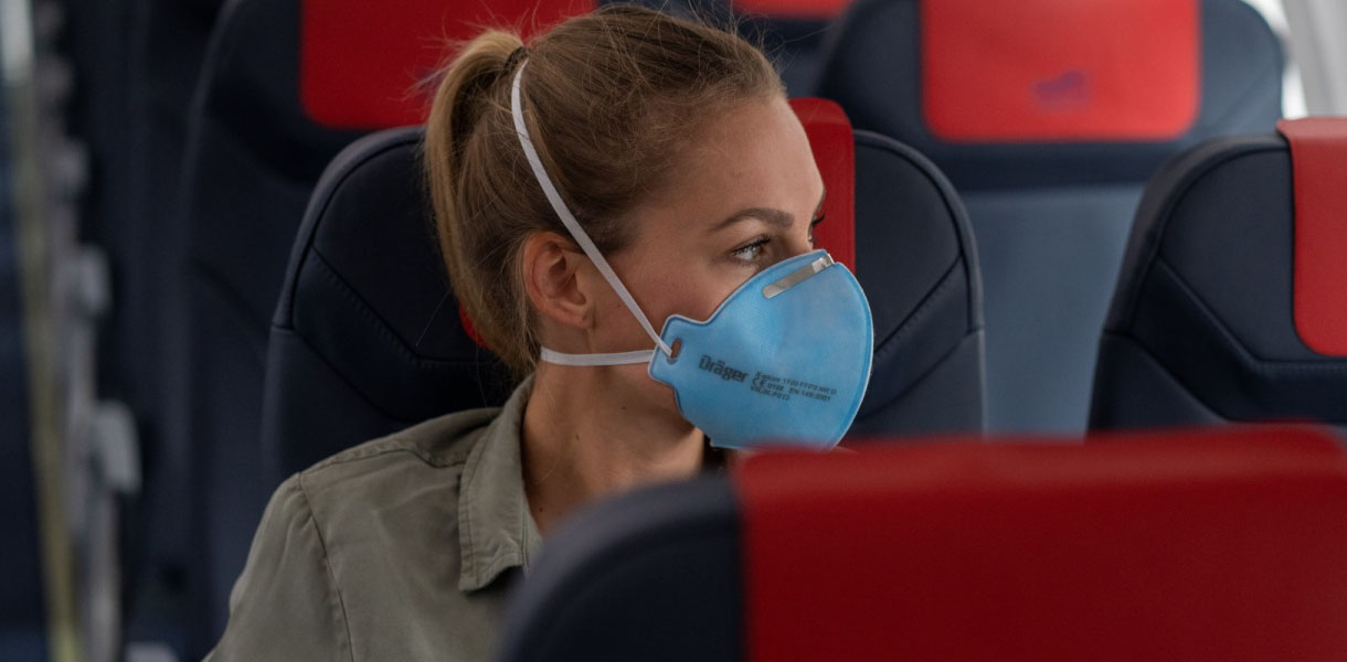 Atemschutzmaske im Reiseflugzeug Person mit Atemschutzmaske sitzt in Flugzeugsitz.