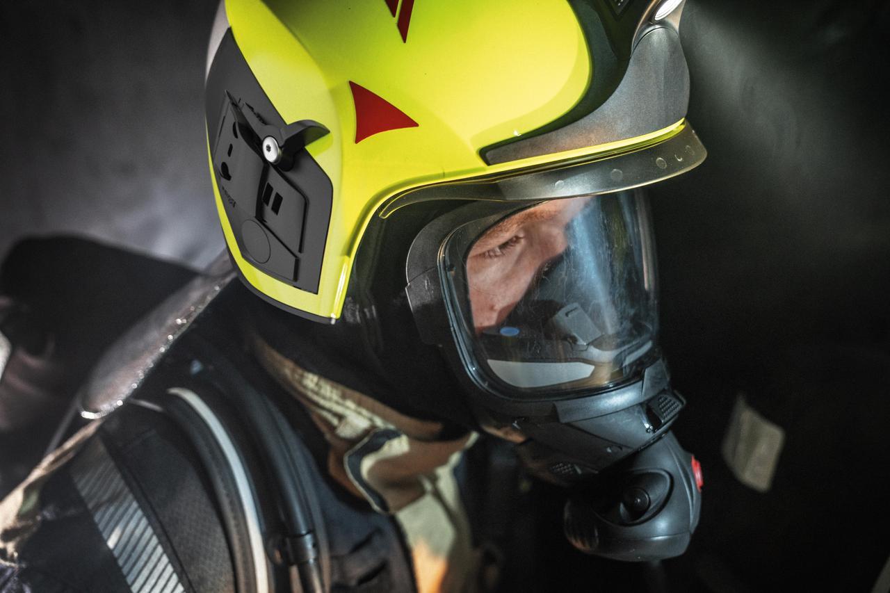 Feuerwehrhelm mit Atemschutzmaske Feuerwehrmann in Schutzkleidung und gelbem Helm mit Atemschutzmaske in einer Einsatzsituation.