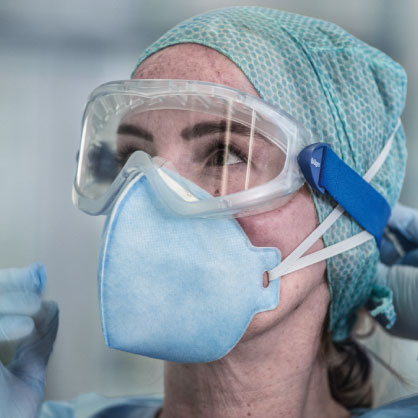 Schutzkleidung im medizinischen Umfeld Person mit FFP-Maske, Schutzbrille und Haube.