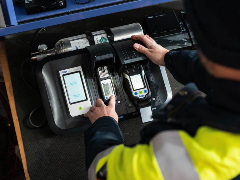 Dräger Gasdetektionsgerät in Aktion Person bedient ein elektronisches Gasdetektionsgerät von Dräger auf einem Tisch.