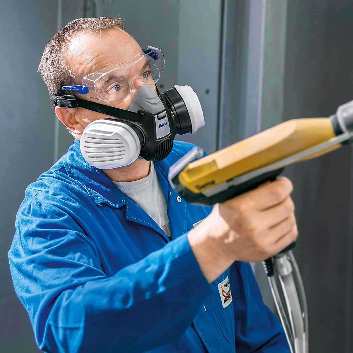 Person trägt Atemschutzmaske beim Sprühen einer Oberfläche.