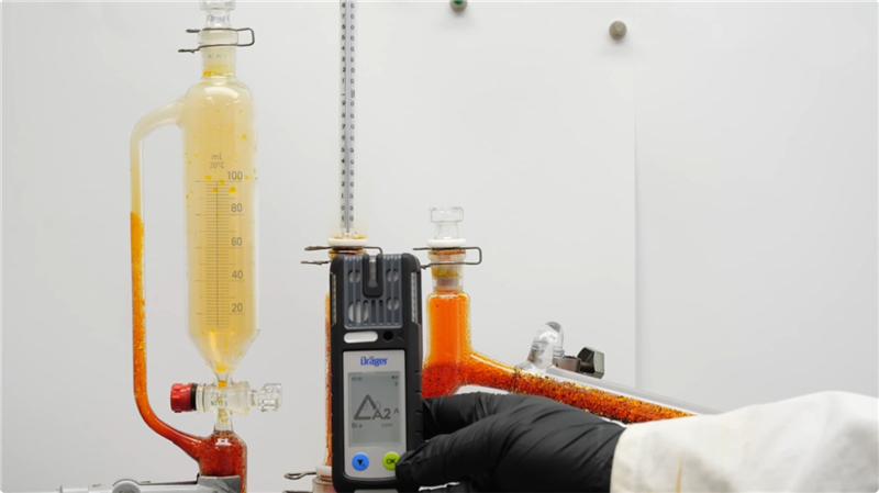 Dräger Gasdetektor im Labor Person hält Dräger Gasdetektor neben chemischer Apparatur im Labor.