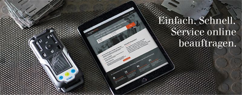 Produktwartung online beauftragen Tablet und Sicherheitstechnikgerät auf Metallfläche.