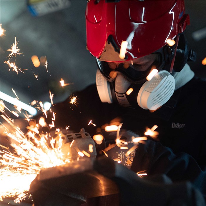 Halbmaske X-plore 3300 von Dräger Person trägt Schutzmaske und Helm beim Schleifen.