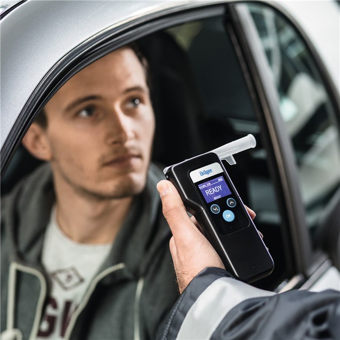 Draeger Alcotest 6000 im Einsatz Person hält ein Draeger Alcotest 6000 vor offenem Autofenster.