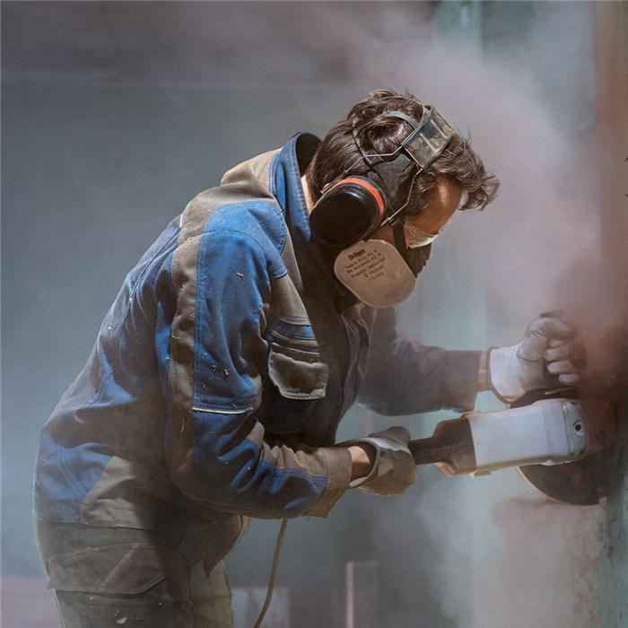 Dräger X-plore 3500 im Einsatz Person trägt Dräger X-plore 3500 Atemschutzmaske bei Arbeit mit Winkelschleifer.