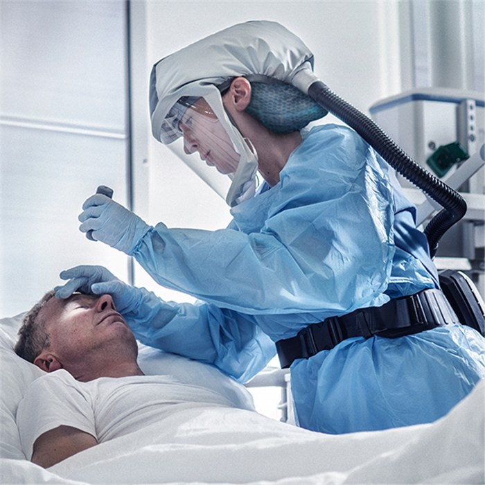 X-plore 8000 mit kurzer Haube Premium Person trägt Schutzkleidung mit Dräger X-plore 8000 Atemschutzgerät beim Patientenkontakt.