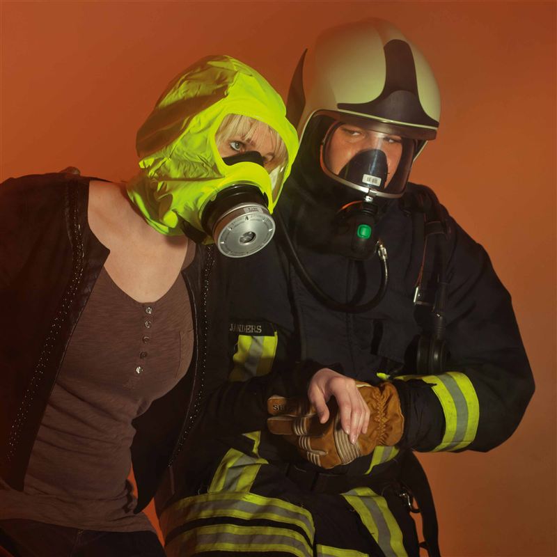 Dräger PARAT 5530 Rettungshaube Person mit gelber Rettungshaube neben Feuerwehrmann.