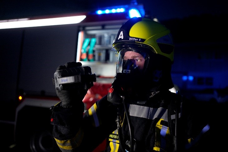 Feuerwehrfrau mit Wärmebildkamera im Einsatz Feuerwehrfrau nutzt Wärmebildkamera vor Einsatzfahrzeug.