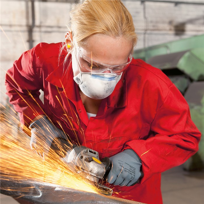 Schutz beim Schleifen mit X-plore 1320 Person schleift Metall mit Funkenflug, rote Schutzkleidung.
