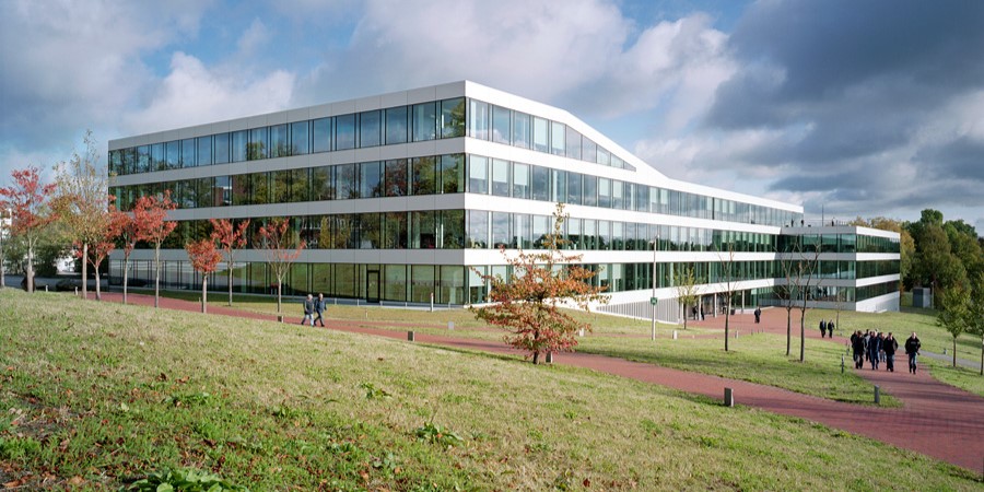 Dräger Gebäude in Lübeck Moderner Flachbau mit Glasfassade und Personen davor.