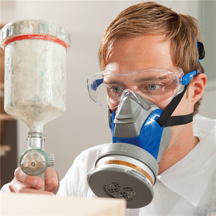 Schutzbrille und Atemmaske im Einsatz Person mit Schutzbrille und Atemmaske bei der Arbeit mit Spraygerät.